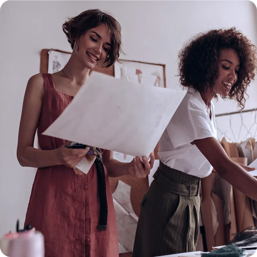 Two fashion designers reviewing a sketch together in an atelier